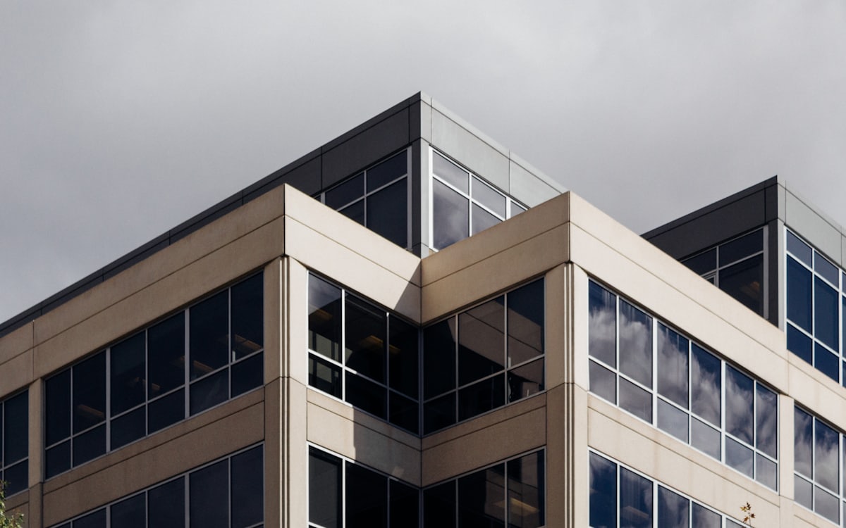 The glazed corner of a modern office building, shown as a website hero.