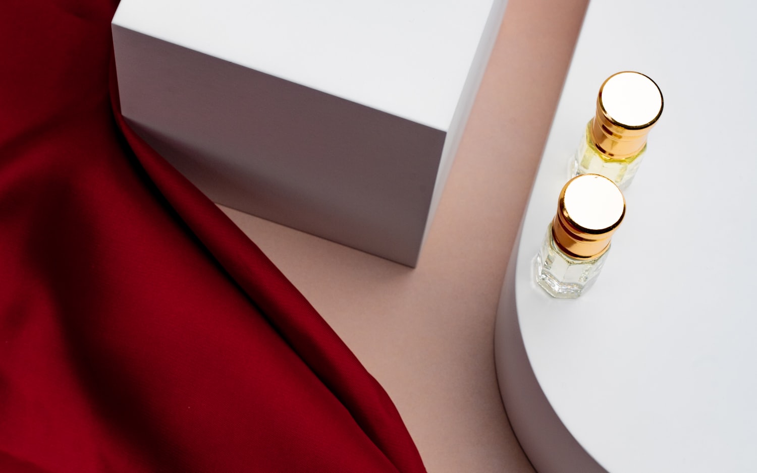 Glass bottles styled on white plinths with draped red silk.