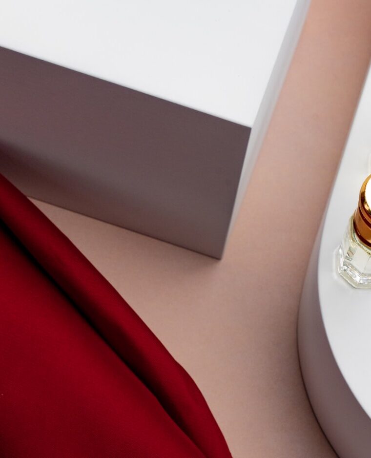 Glass bottles styled on white plinths with draped red silk.